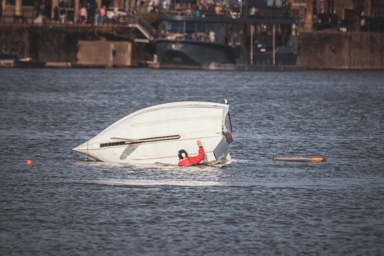 Boat turned on its side and the person is on the water