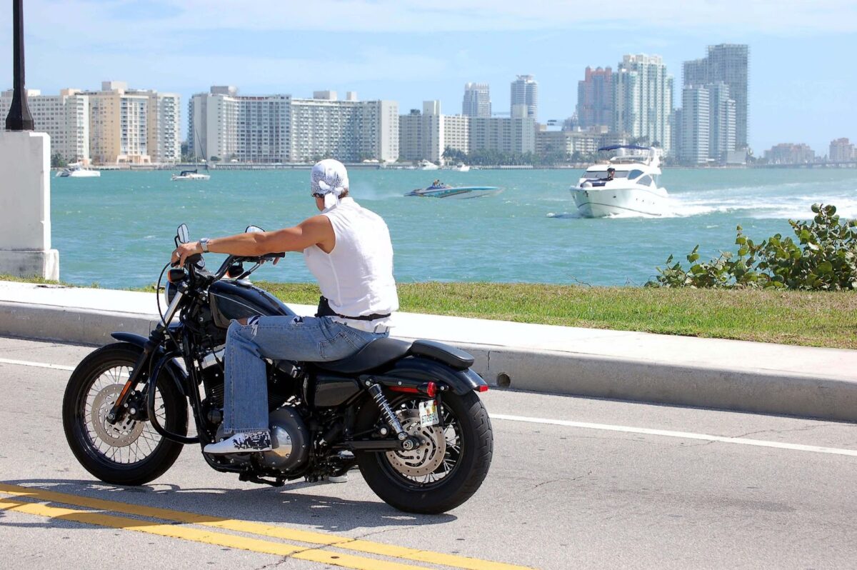 man on black motorcycle riding next to Miami waters