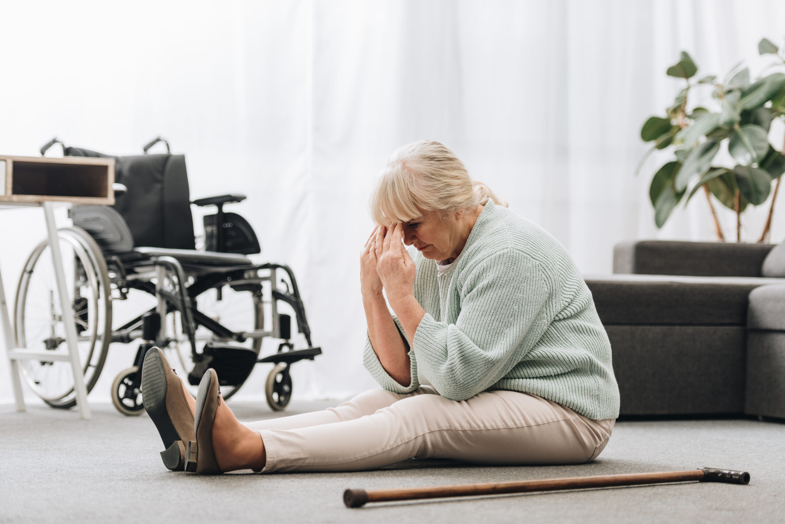 Upset retired woman sitting on floor: suffering nursing home negligence